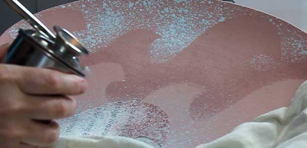 Glaze being sprayed onto large plate.